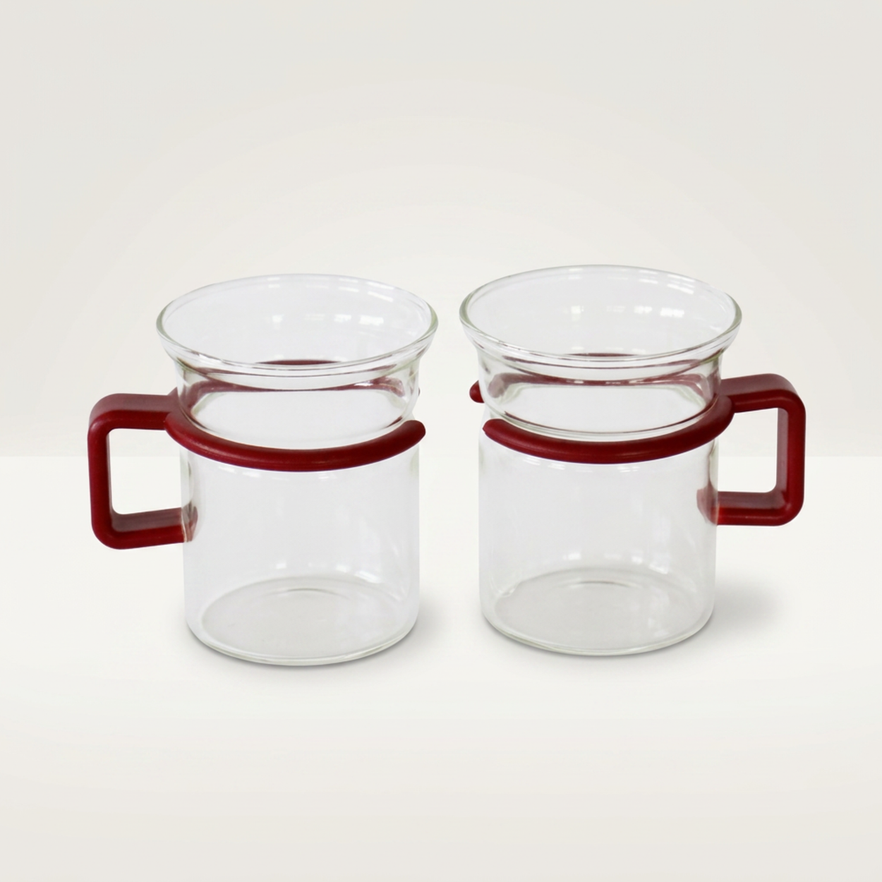 Two clear glass mugs with red handles on a white background