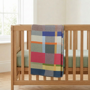 Wallace Sewell Gwynne Baby Blanket draped over oak crib.