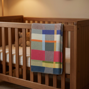 Wooden crib with a colorful checkered blanket draped over the side