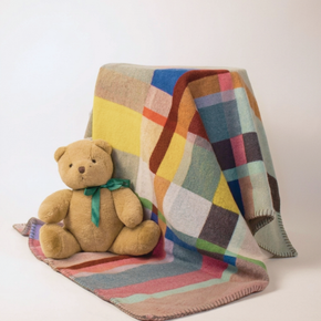 Colorful patchwork blanket with a teddy bear on a white background