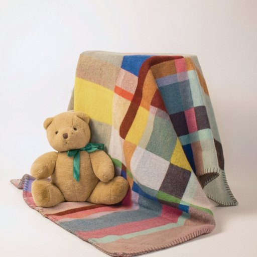 Colorful patchwork blanket with a teddy bear on a white background
