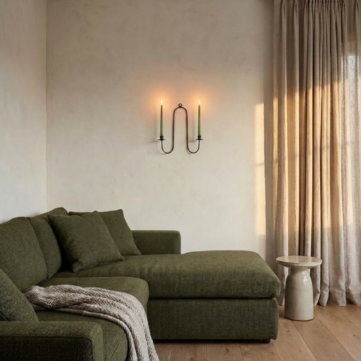 Wrought iron double candle wall sconce with Green sectional sofa in a living room with neutral decor