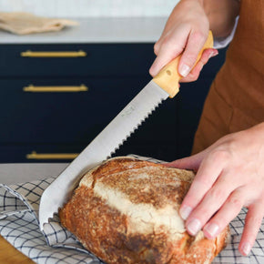 Woman slicing bread with Pallares Solsona 25cm Box Wood Stainless Steel Bread Knife