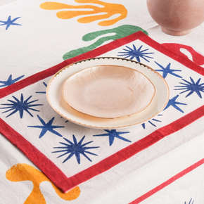 Colourful placemat with organic shapes and star patterns, placed on a table with a matching tablecloth.