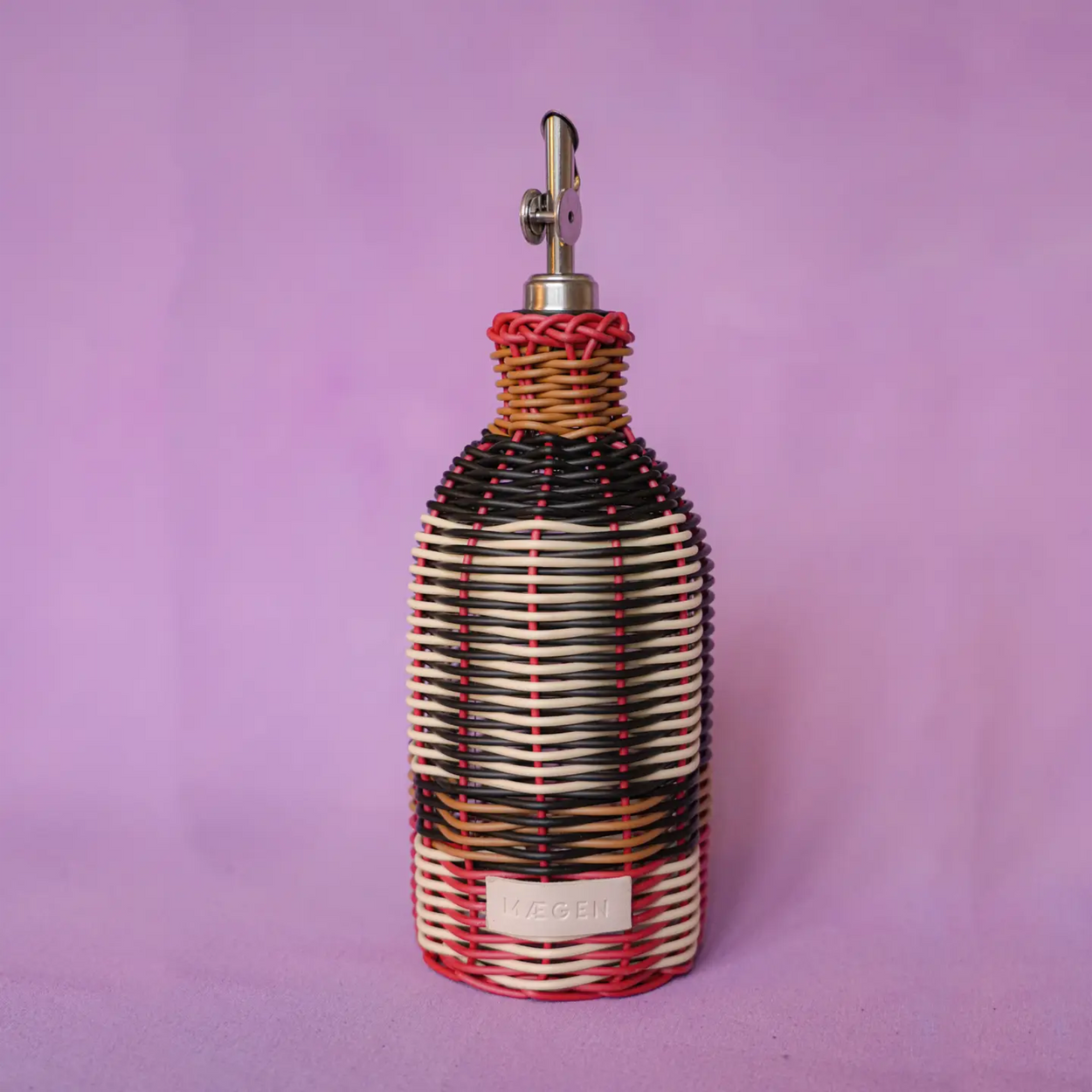 Decorative bottle with woven design and metallic top on a purple background