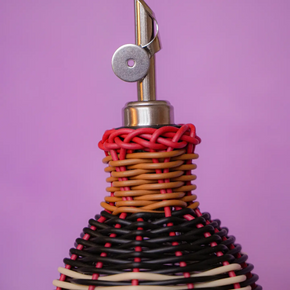Bottle and spout with woven design on a purple background
