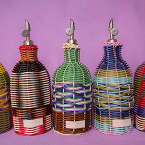 Five colorful woven bottle dispensers on a purple background