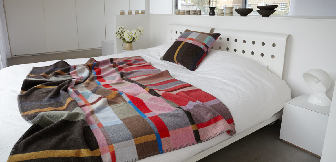 Lasdun Wallace Sewell blanket strewn across white bed with matching pillow.