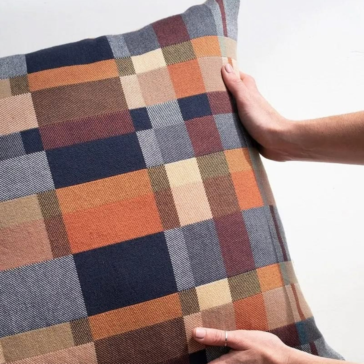 Mungo Karoo Plaid double cotton  patterned pillow held by a person against a white background