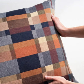 Mungo Karoo Plaid double cotton  patterned pillow held by a person against a white background