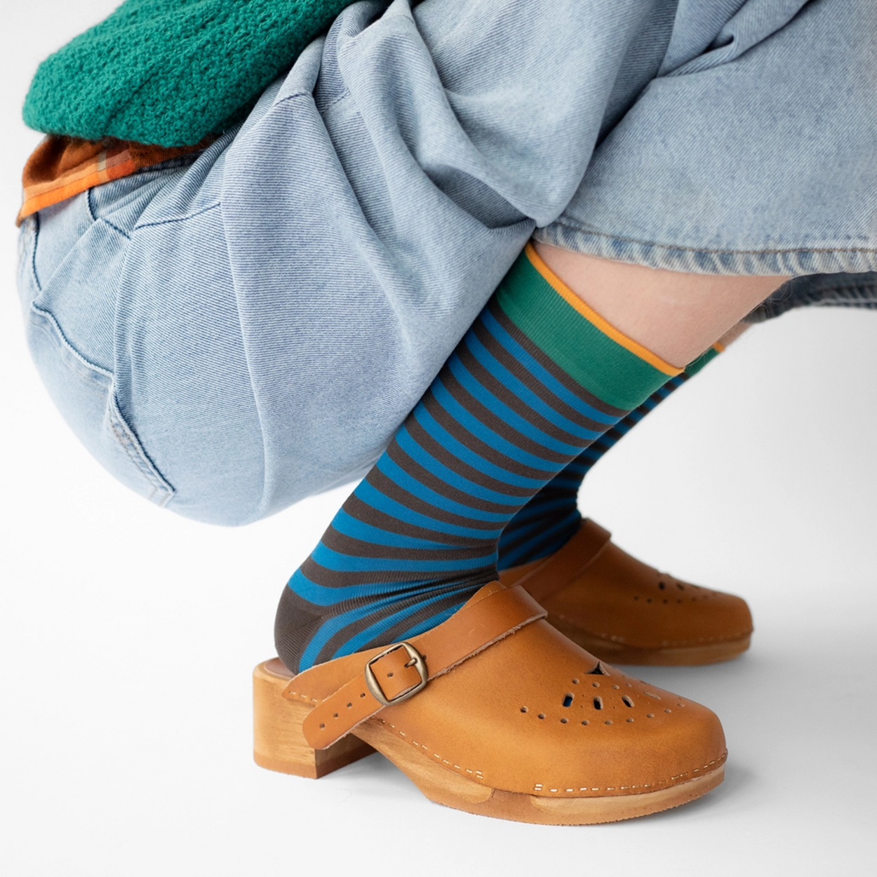 Woman in blue jeans wearing Bonne Maison Blue Black Stripe socks against a white backdrop.