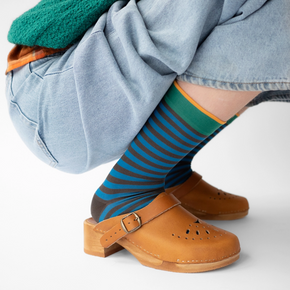 Woman in blue jeans wearing Bonne Maison Blue Black Stripe socks against a white backdrop.