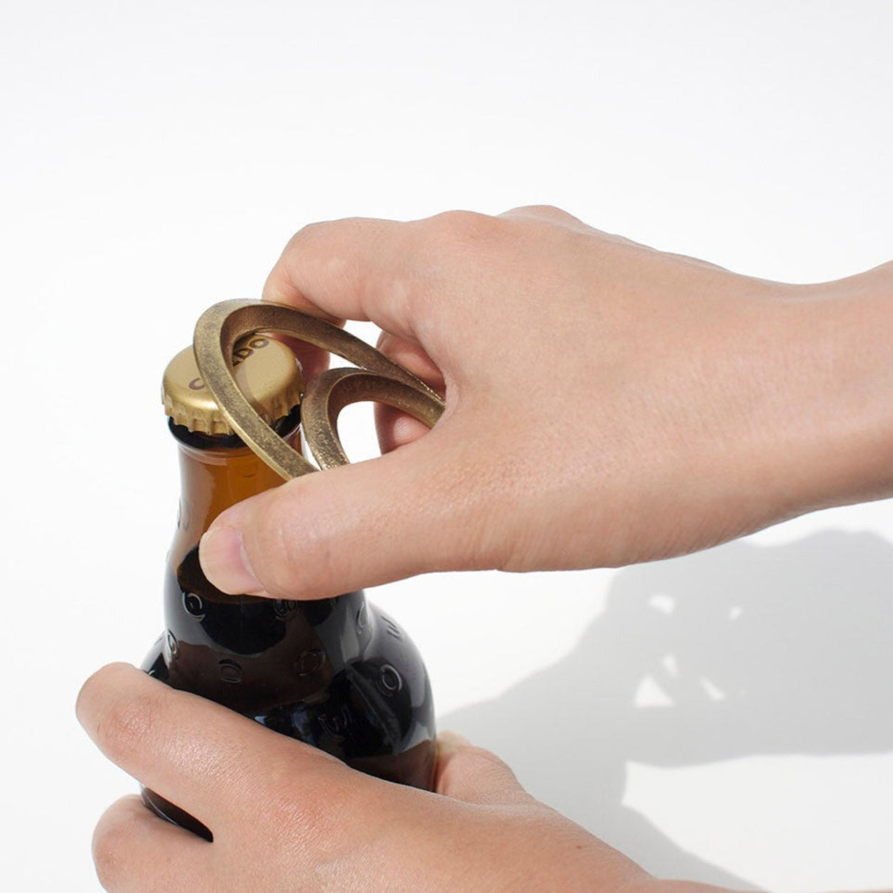 Person using Futagami Eclipse Bottle Opener to open beer bottle.