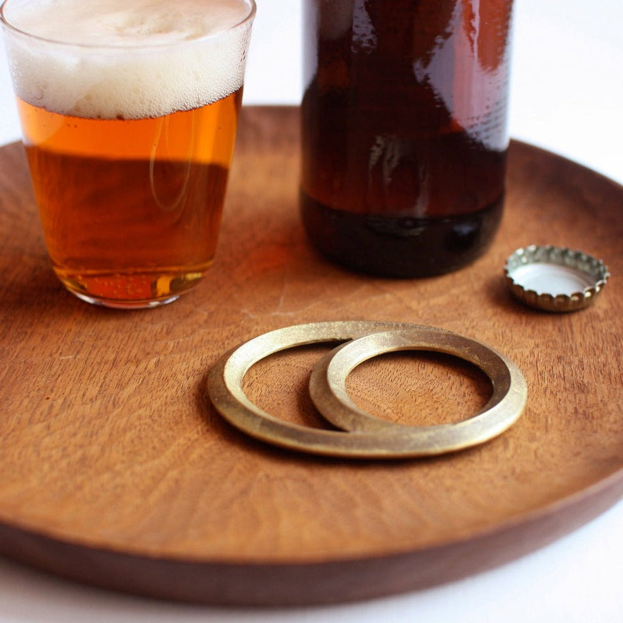 Futagami Eclipse Bottle Opener on wood plate with beer bottle and glass.