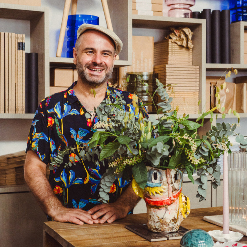 Florian Tanzer with a bouquet of flowers in his handmade vase in an art studio setting