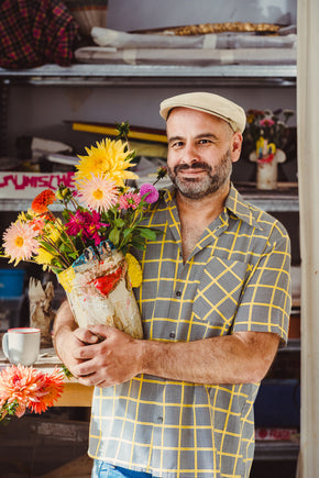 Florian Tanzer holding a bouquet of flowers in his handmade vase in an art studio setting