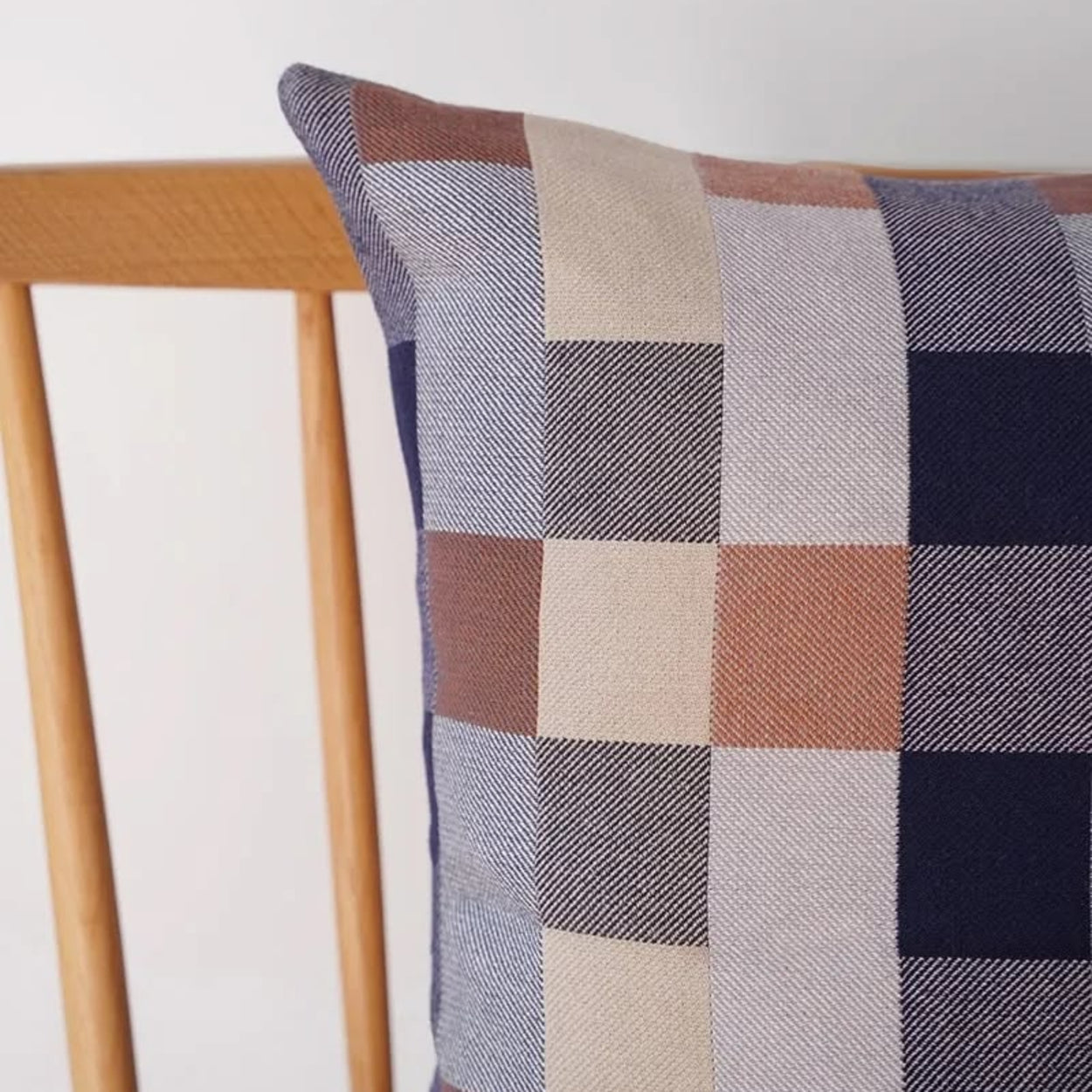 Close up of Mungo Seven Seas Checkered double cotton pillow on a wooden chair against a white background
