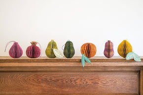 Colorful paper pumpkins on a wooden surface with a white background