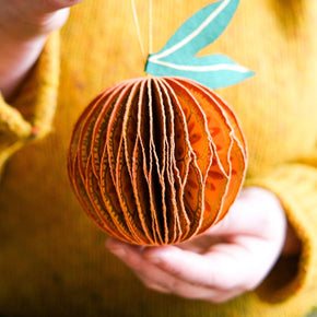 Hand holding a decorative paper apple with a yellow background