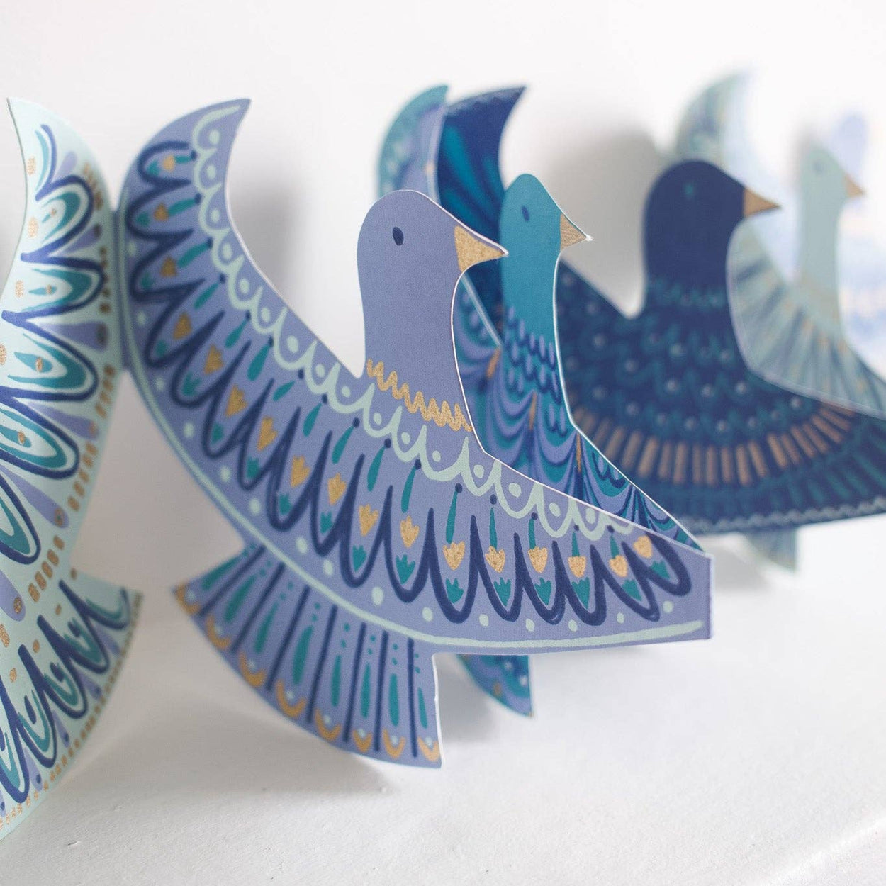 Decorative paper birds with blue and white patterns on a white background