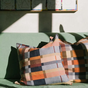 Mungo Karoo Colourful double cotton checkered pillows on a green couch with a wall of colourful artwork in the background.