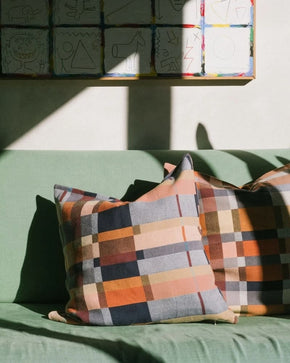 Mungo Karoo Colourful double cotton checkered pillows on a green couch with a wall of colourful artwork in the background.