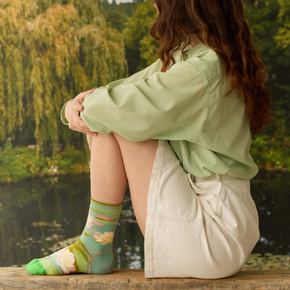 Woman in beige shorts wearing Waterlily Bonne Maison socks on garden backdrop.