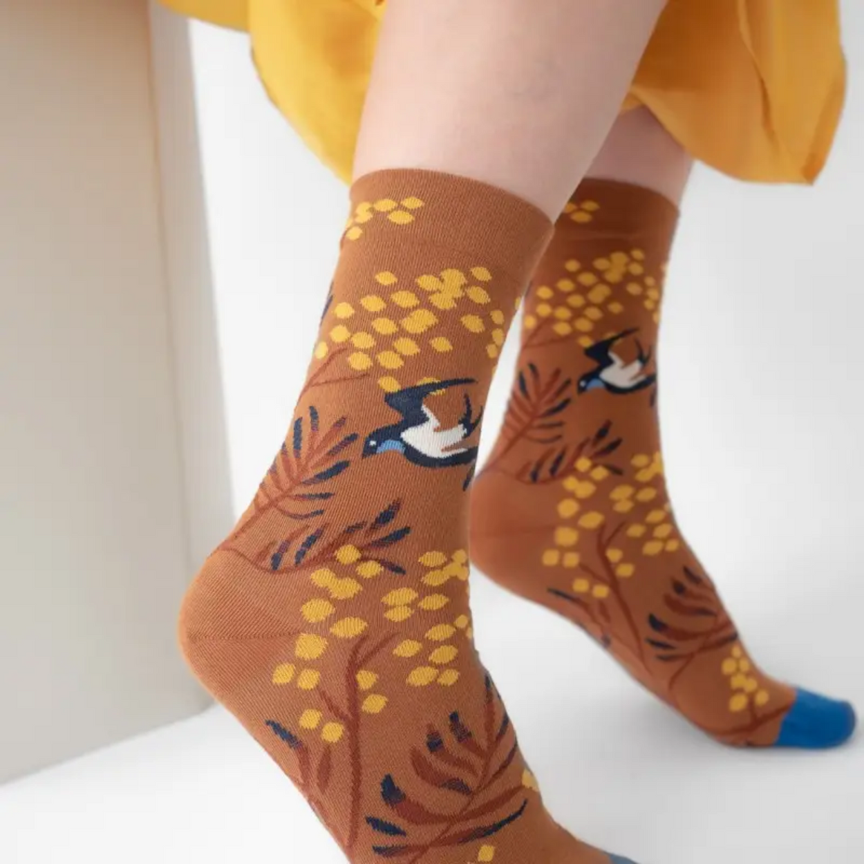 Woman in yellow skirt wearing Caramel Mimosa Bonne Maison socks on white backdrop.