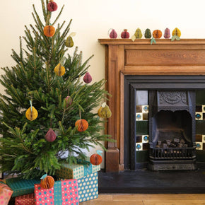 Decorated Christmas tree with colorful ornaments and presents in front of a fireplace.