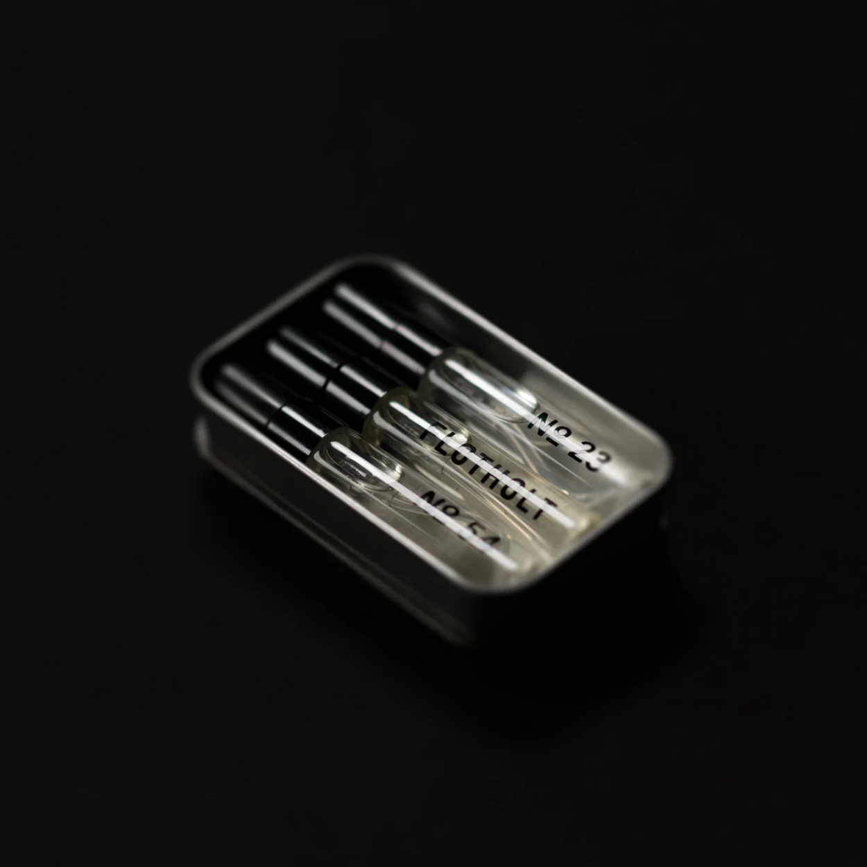 Set of 5ml decant perfumes in a metal case on a black background