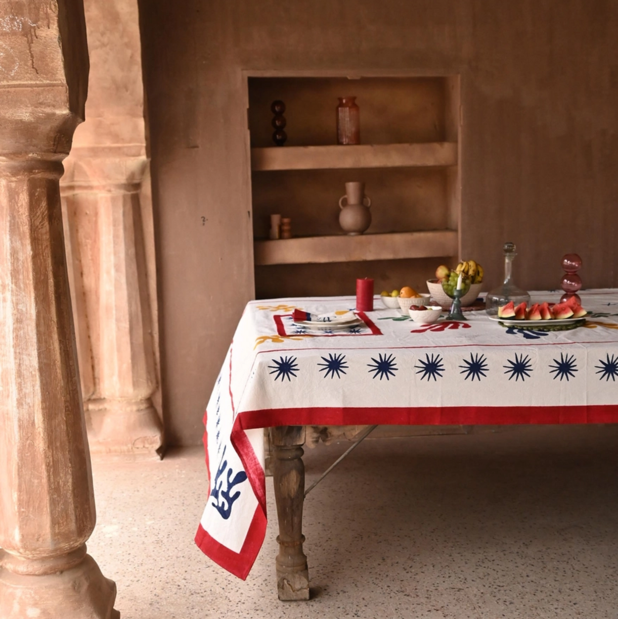 Table set with a decorative tablecloth in a rustic interior setting.