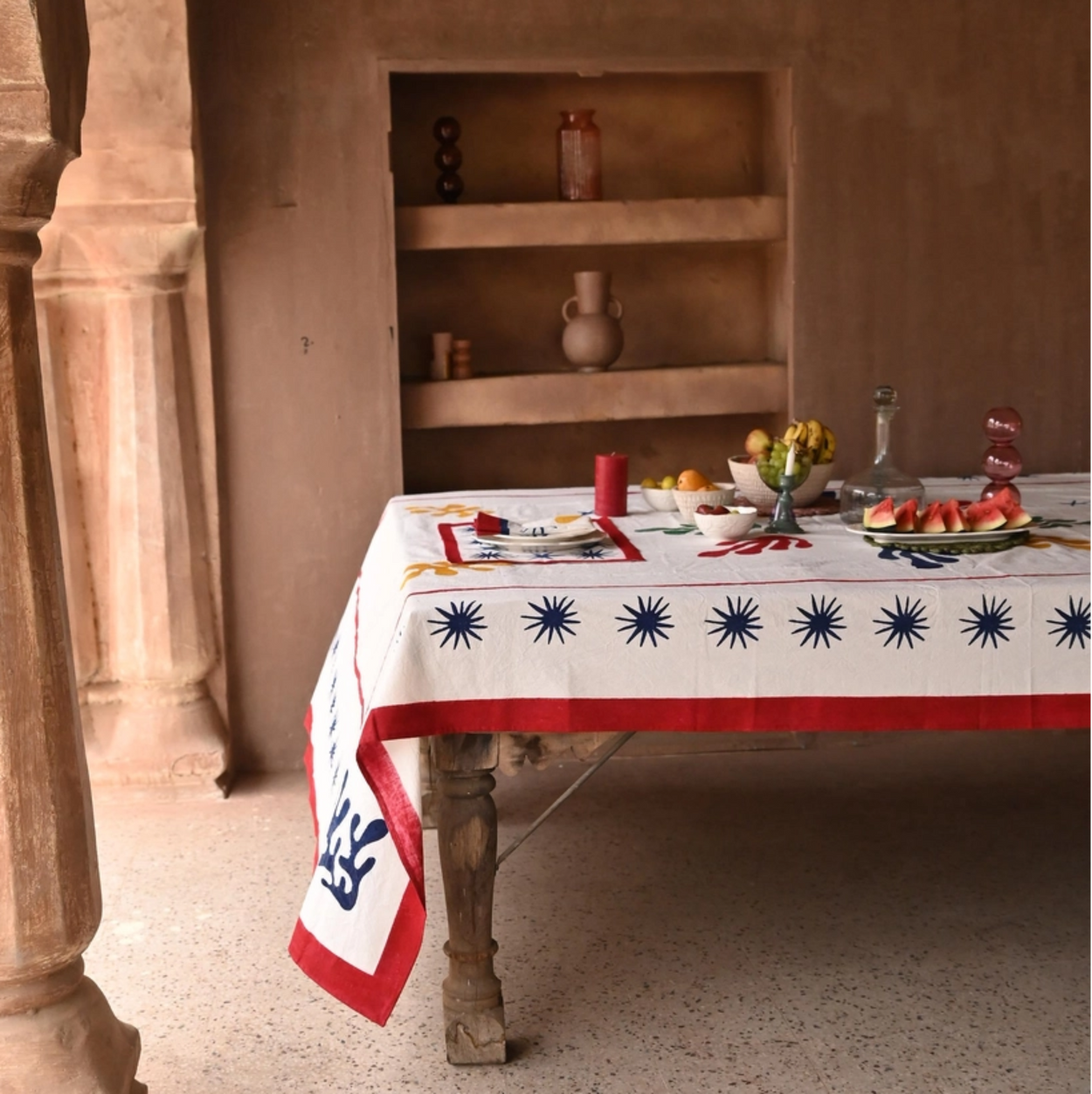 Table set with a decorative tablecloth in a rustic interior setting.