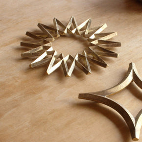 Group of Futagami trivets including a Futagami Brass Galaxy Trivet on wood table.