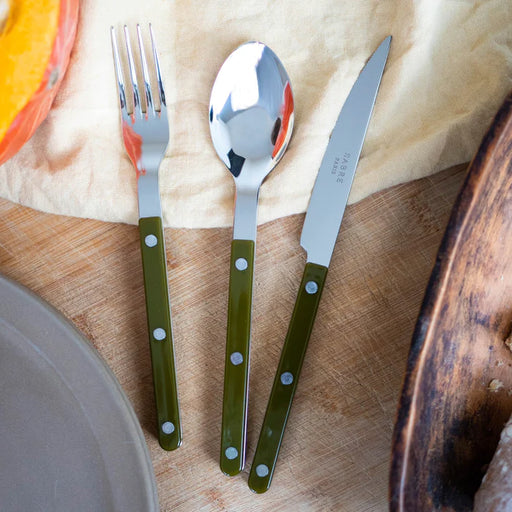 Sabre Paris Bistrot in Fern Green cutlery on wooden table with beige napkin.