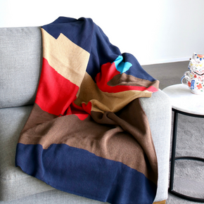 Modern cotton navy blue knit throw blanket on grey sofa close up