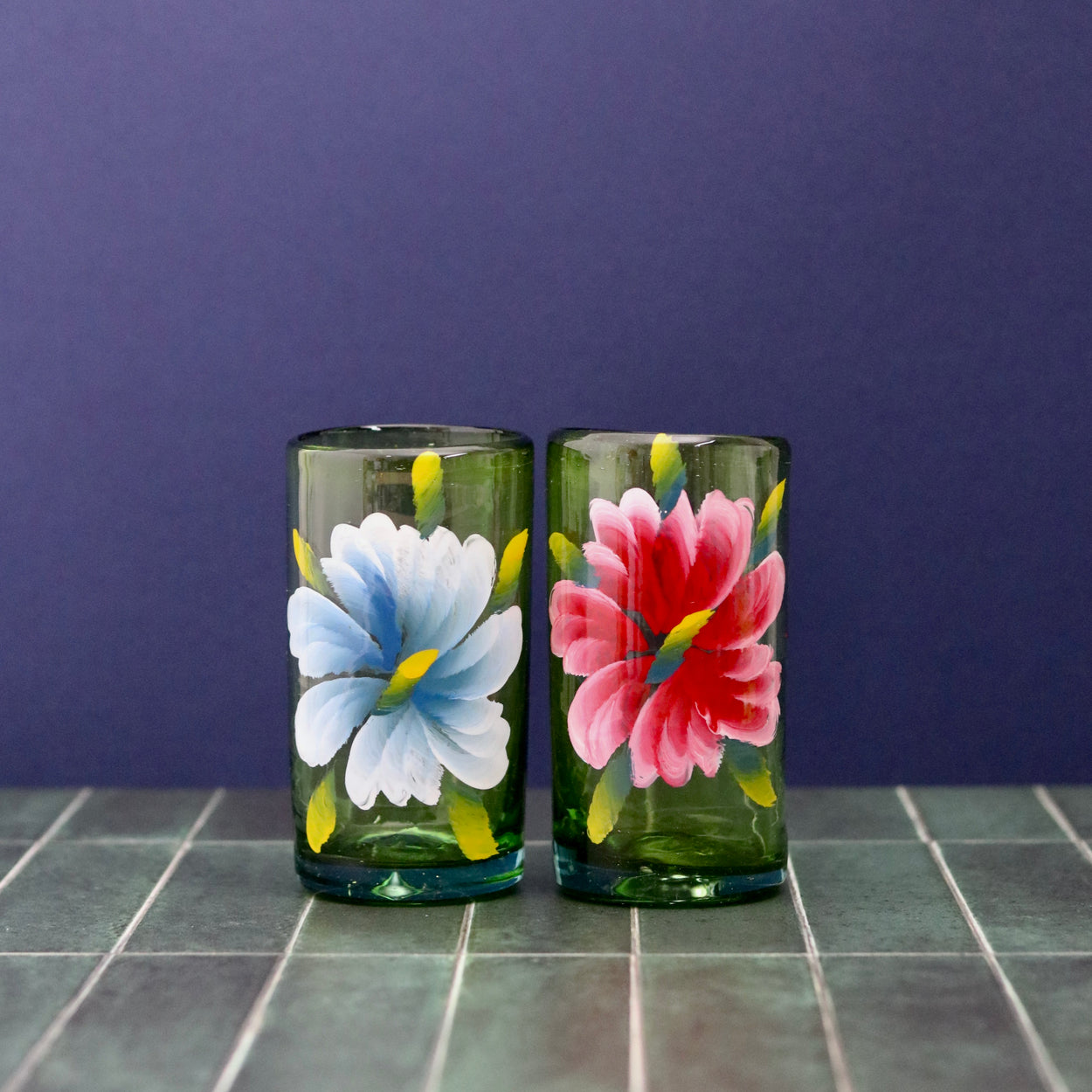 Floral hand painted glass tumblers x 2 against blue background