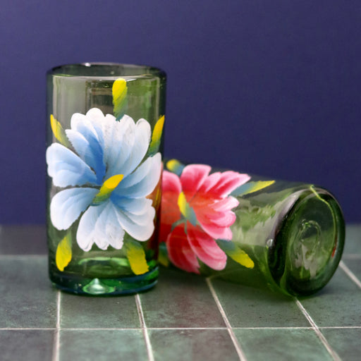 Floral hand painted glass tumblers x 2 against blue background, red lying down