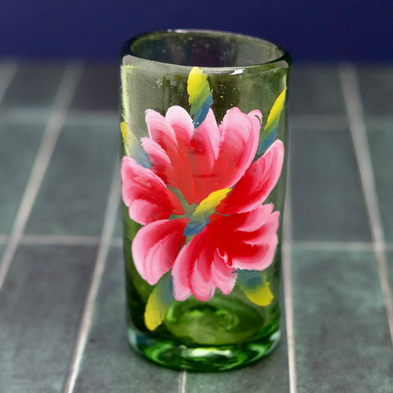 Floral hand painted glass tumbler against blue background