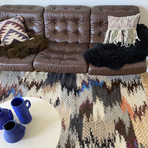 Hand Woven Pure Wool Rug - Blue close up with leather couch, round table and blue vases.