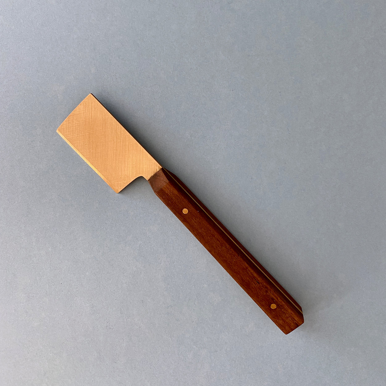 Handmade Walnut & Brass cheese knife against blue background