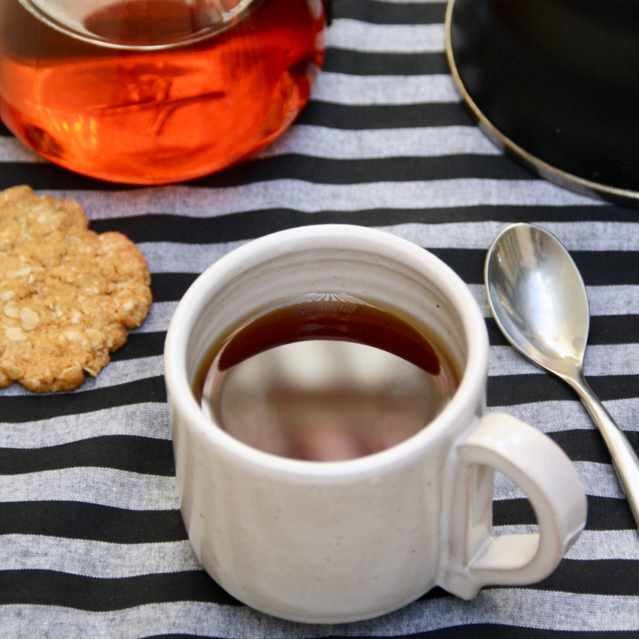 Handmade Ceramic Coffee Mug - Large, by Richard Beauchamp on striped background.