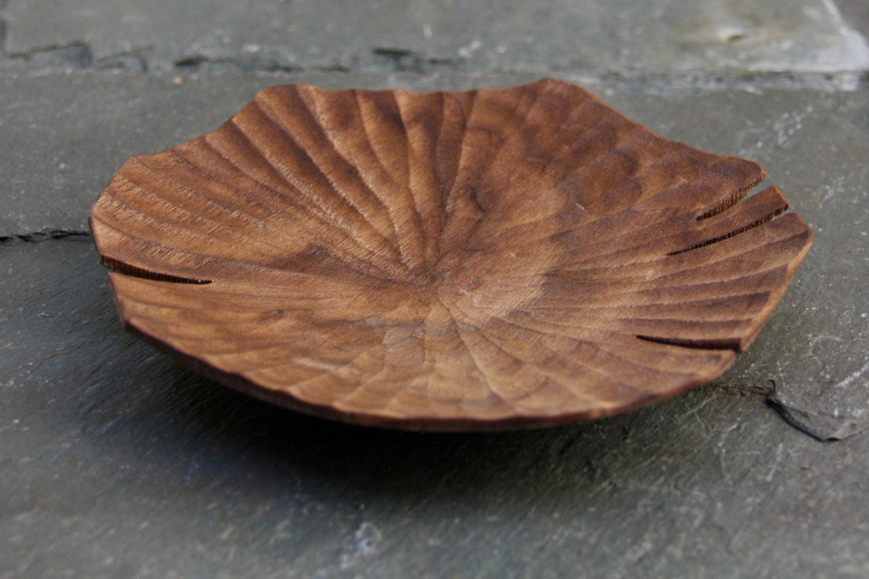 Hand carved Lotus leaf walnut wood plate on slate background, close up