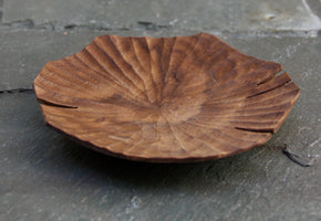 Hand carved Lotus leaf walnut wood plate on slate background, close up