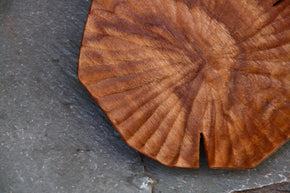Hand carved Lotus leaf walnut wood plate, close up against slate