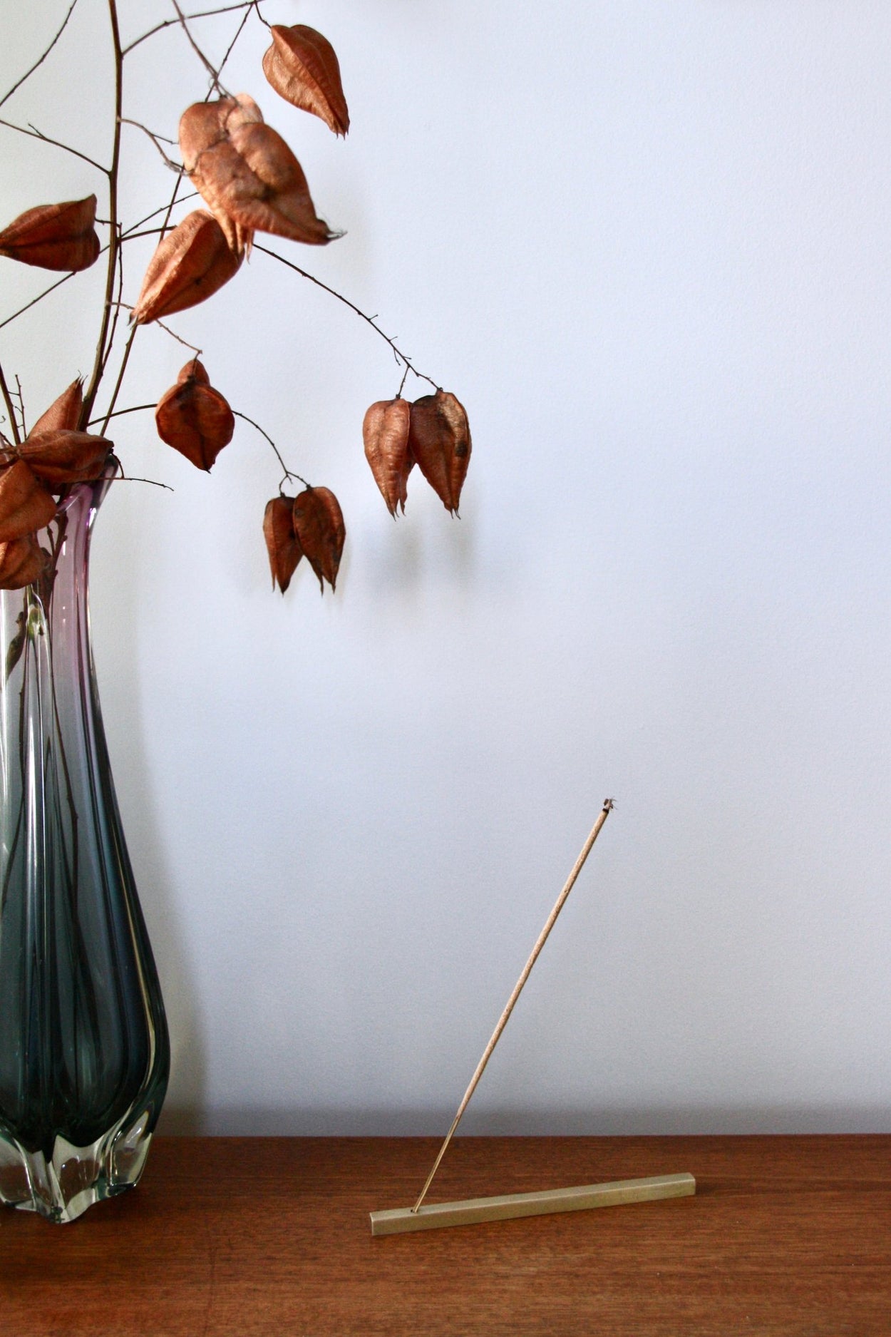 Juniper Ridge Campfire Incense - White Sage, burning in metal incense holder on wood shelf with vase and flowers