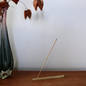 Juniper Ridge Campfire Incense - Douglas Fir, burns in metal incense holder on wood shelf with vase and flowers.