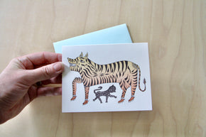 Hand holding Tiger Letterpress Greeting Card with pale blue envelope on pale wood.