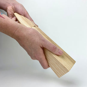 Hand using Ash wood salt grinder by Martino Gamper with white background