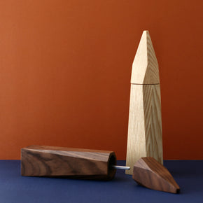 Walnut (lying down) and Ash wood salt and pepper grinders by Martino Gamper with blue and brown background
