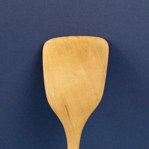 Close up of Handmade Pear Wood Kitchen Spatula against blue background